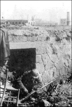 <p>Soldati tedeschi intenti a pulire la loro MG42. Sullo sfondo le rovine di Aprilia.</p>