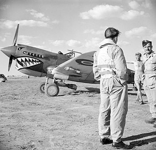 <p class='eng'>Squadron-Leader P F Illingworth (back to camera), the Commanding Officer of No. 112 Squadron RAF, discusses a target with Army officers, prior to setting out on a sortie from Foggia, Italy. Behind them is his Curtiss Kittyhawk Mark III., the plane might be FR864 GA-M the four just visible in the picture, that plane was shot down, 20 Dec 1943.<br /><br />http://raf-112-squadron.org/ORB.html</p>